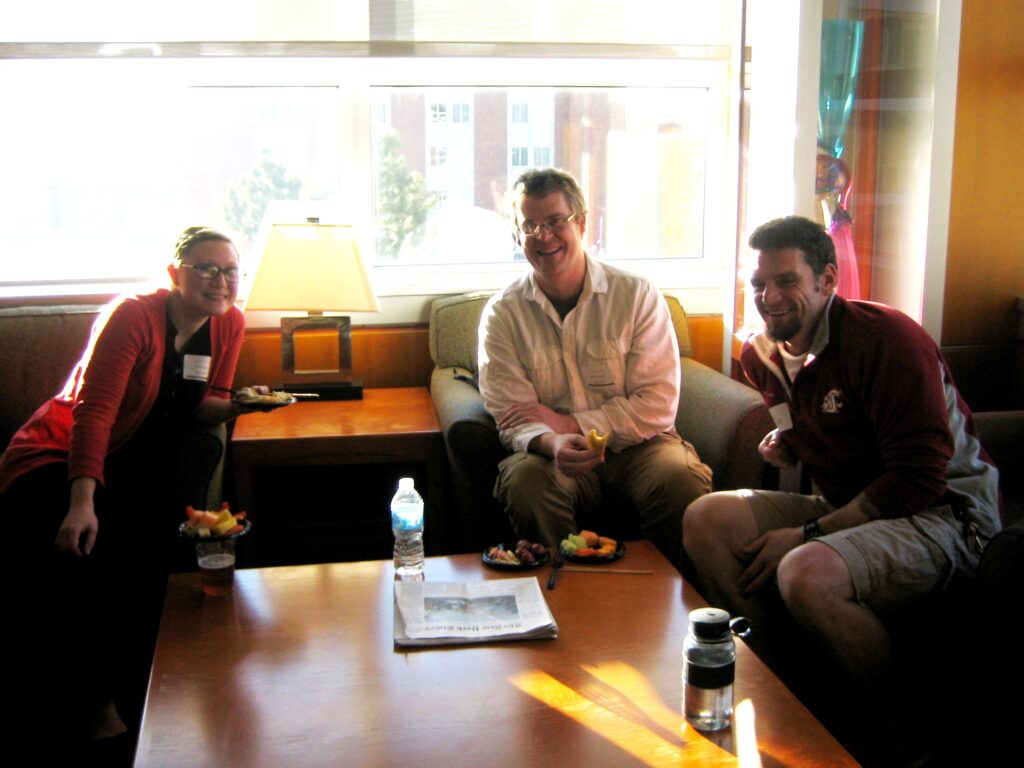 Three people are seated, smiling.