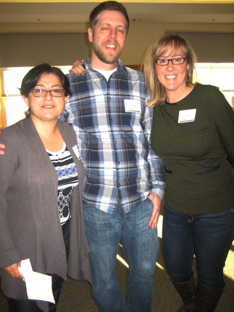 Three people stand together and smile for a picture.
