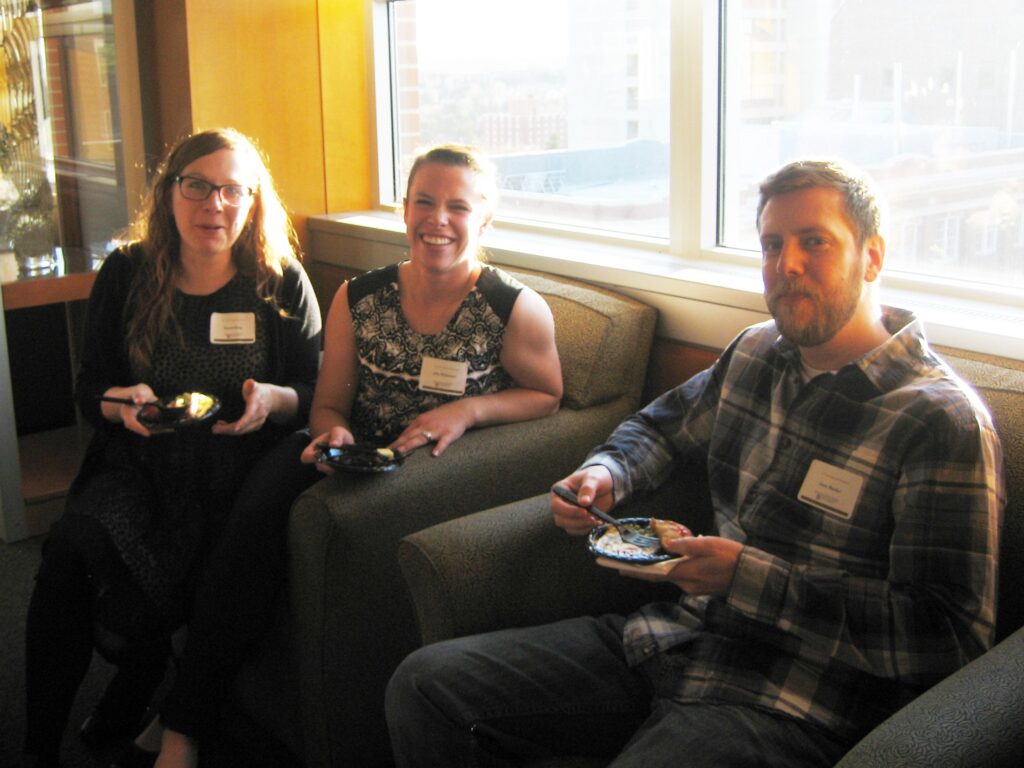 Three people are seated, smiling.