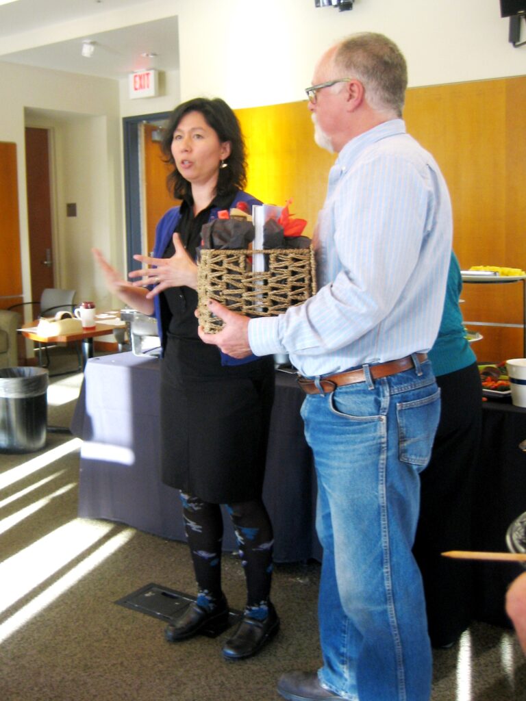 Laura Lavine stands next to Dr. Shepphard, who is holding a basket full of stuff.