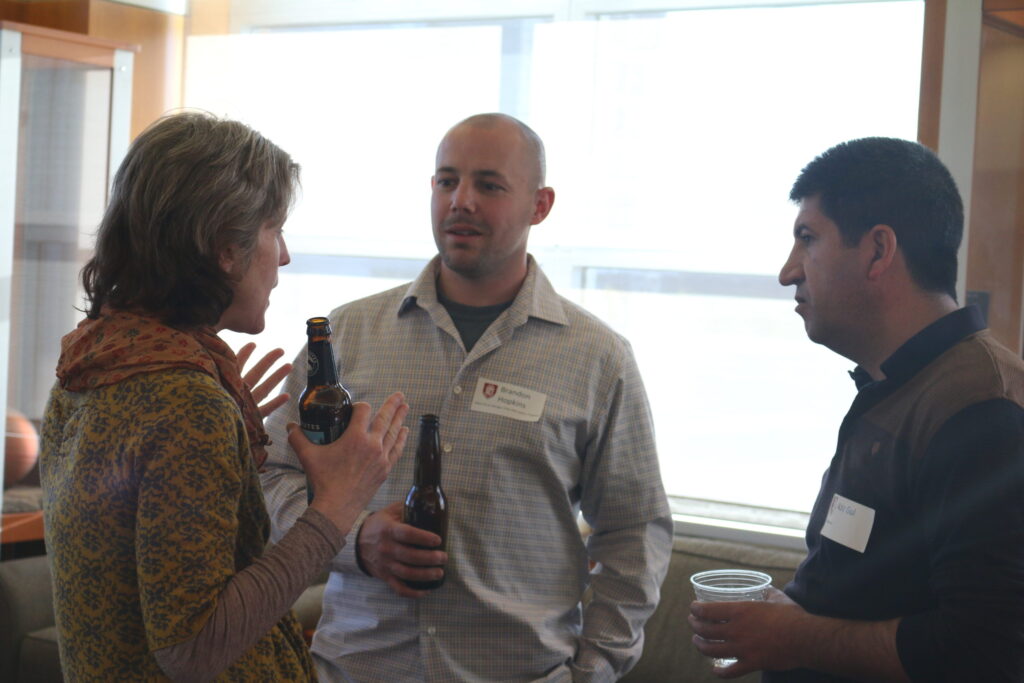 Brandon Hopkins, Erin O'Rourke, and Aziz Gul stand together and chat.