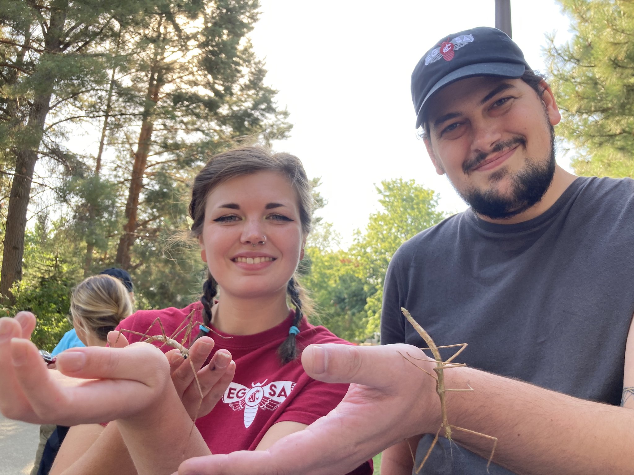Two students hold up stick bugs.