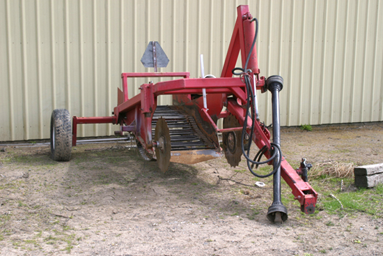 A picture of a red, one row level bed harvester.