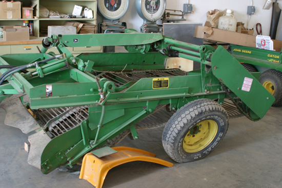 A picture of a green, two row, level bed harvester.