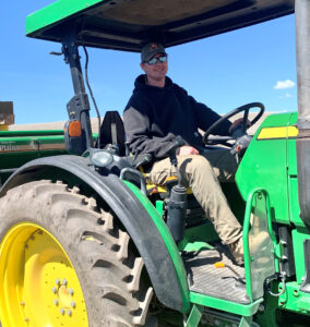 Photo of former graduate student Joe Townsend driving a tractor at the WSU Othello research farm