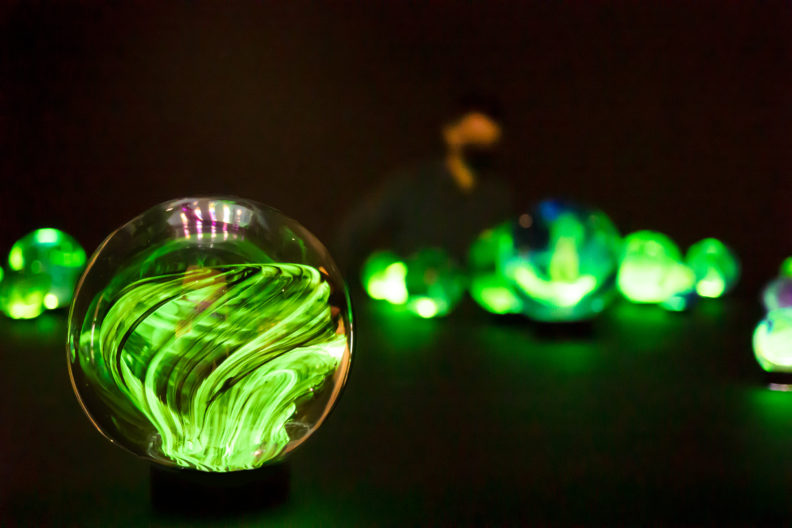 Photo of green glass sculptures and person in background.