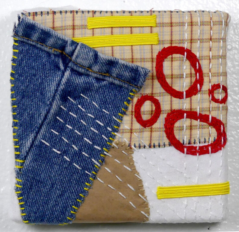 Fabric collage with varied shapes and stitching. 