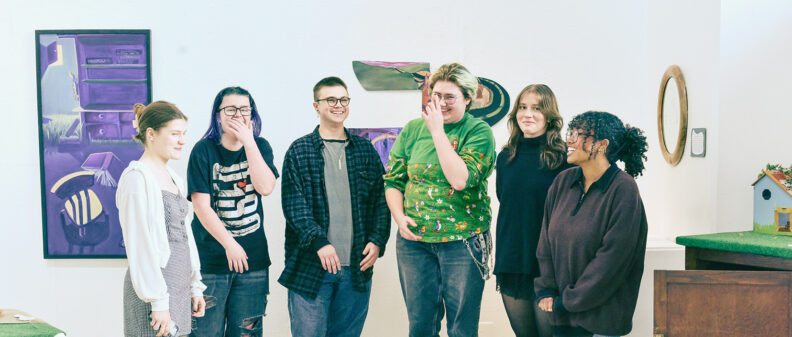 Group of students smiling and laughing in gallery.