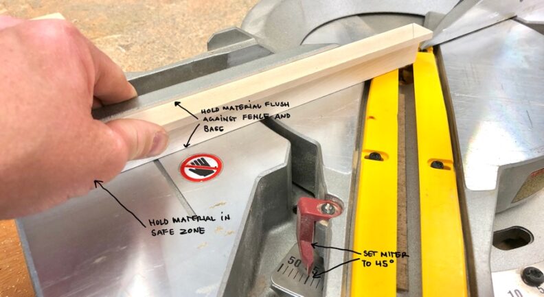 Demonstration of making a cut with the miter saw. Instructions: Hold material flush against fence and base; hold material in safe zone; set miter to 45°. Image links to larger version.