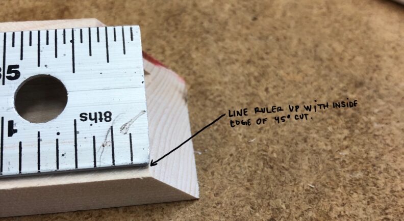 Closeup of a ruler on the cut material. Instructions to line ruler up with inside edge of 45° cut. Image links to larger version.