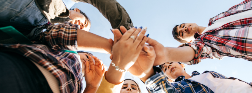 Group of people stacking hands together.