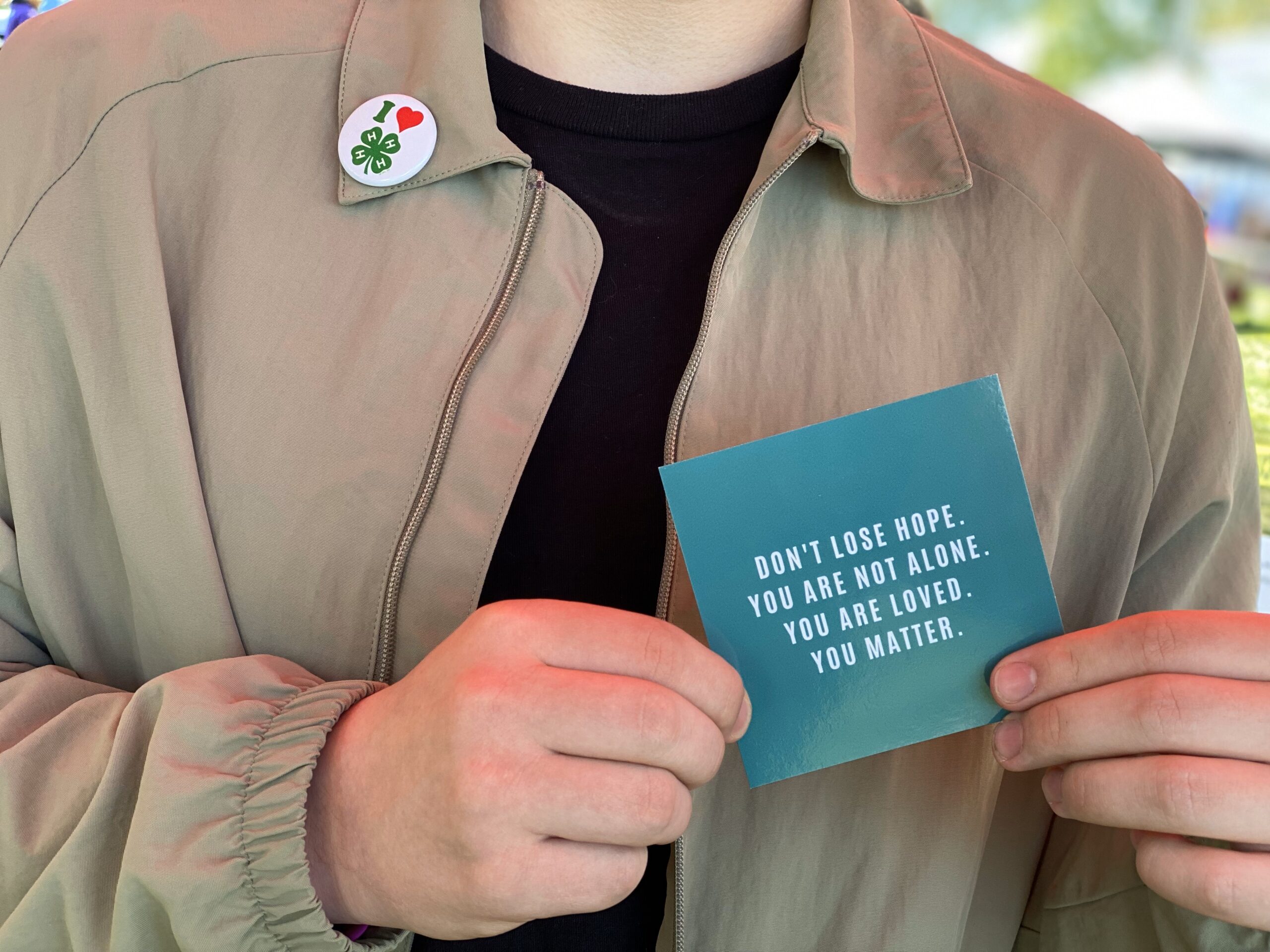 Teen holding card which reads Don't lose hope. You are not alone. You are loved. You matter.