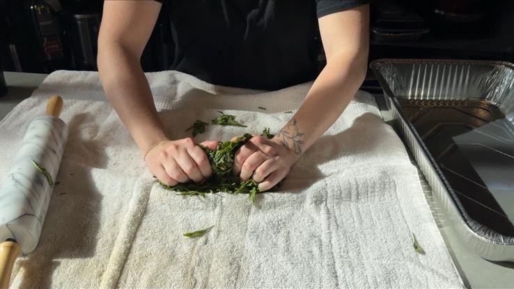 close up of a person kneading tea leaves on top of a white towel