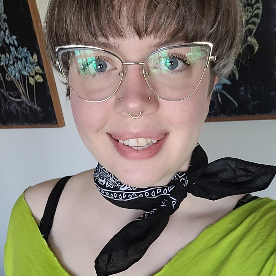 a person with short brown hair, wearing glasses and a bright green shirt