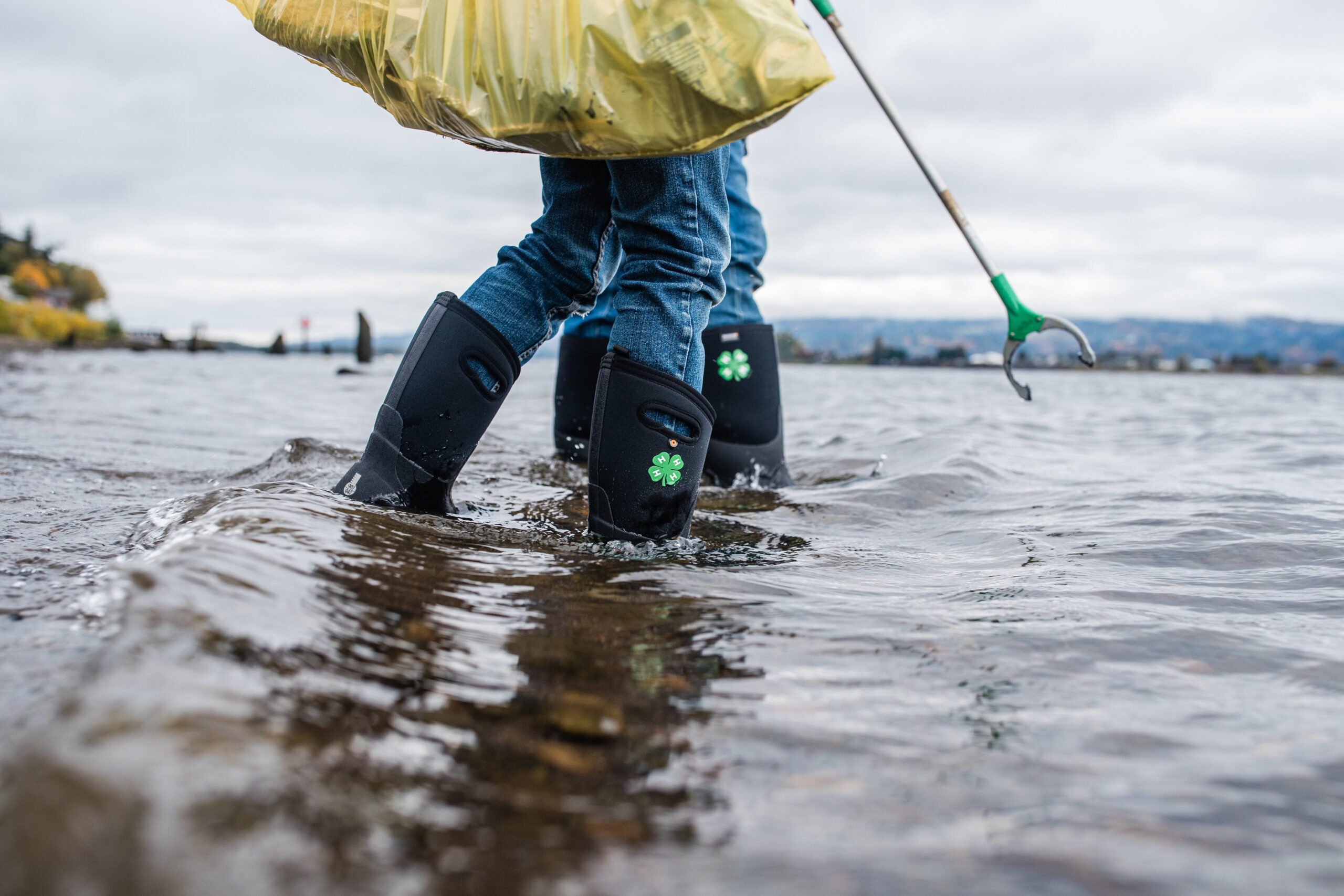 4-H member in boot with clover on them cleaning water