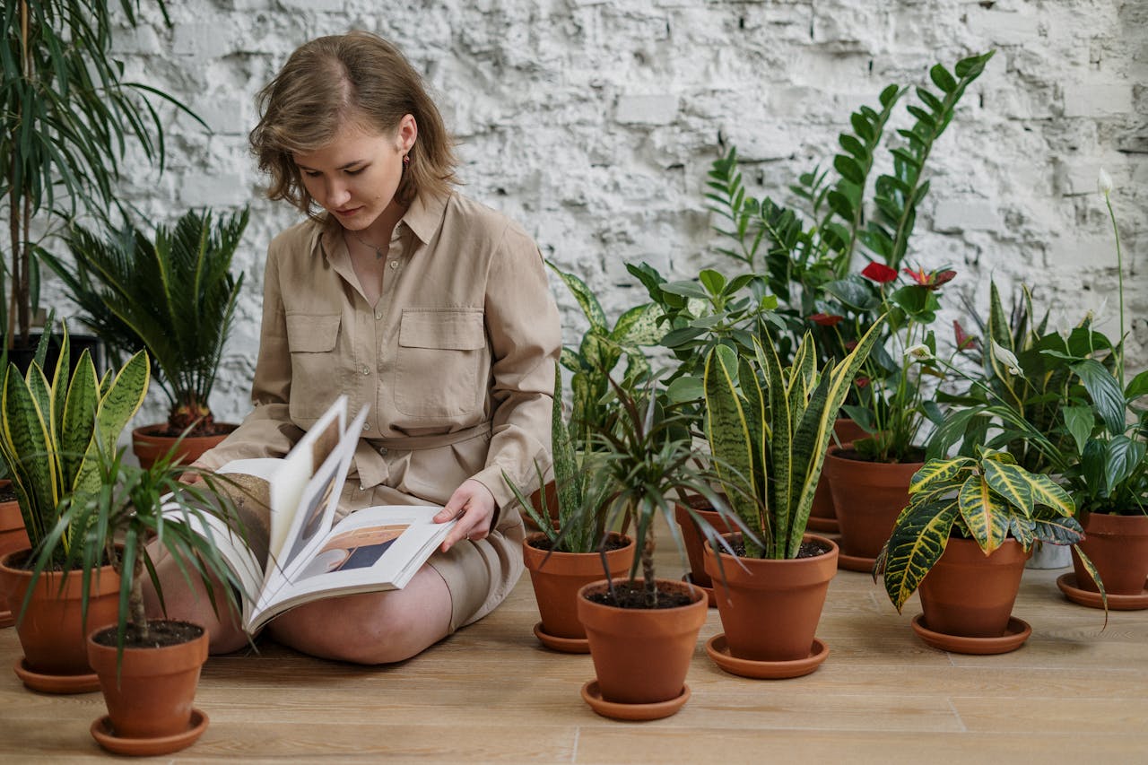 Woman with book sitting amidst potted plants