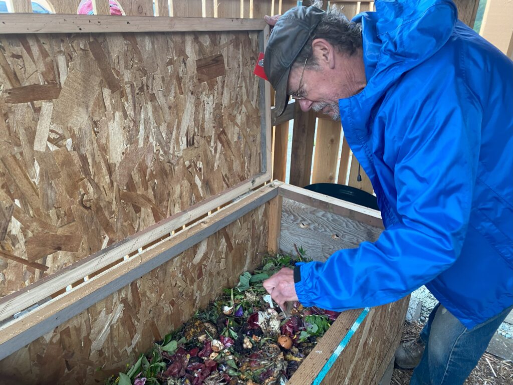 Man adding food scraps to worm bin.