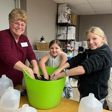 Woman and two girls digging into a bucket of soil