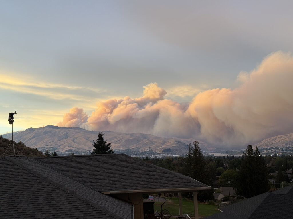 Smoke from wildfire seen in the distance behind hills