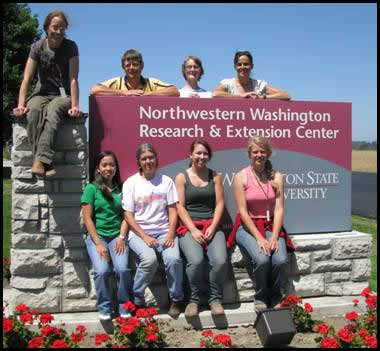 Eight people grouped around a sign reading Northwestern Washington Research & Extension Center.