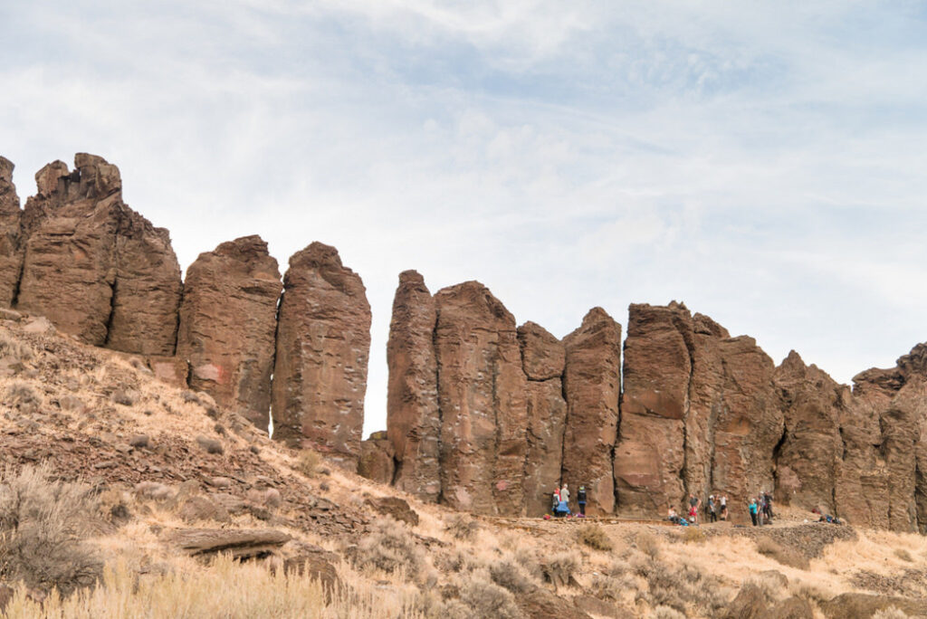 landscape view of climbers looking very small in front of columnar basalt formations.
