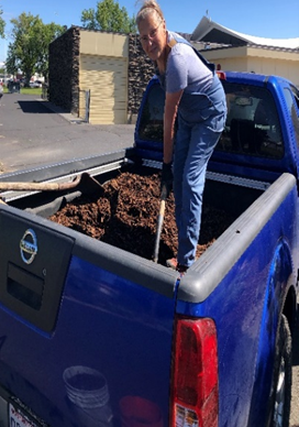 Mary in the bed of a pickup with mulch at the Moses Lake demonstration garden