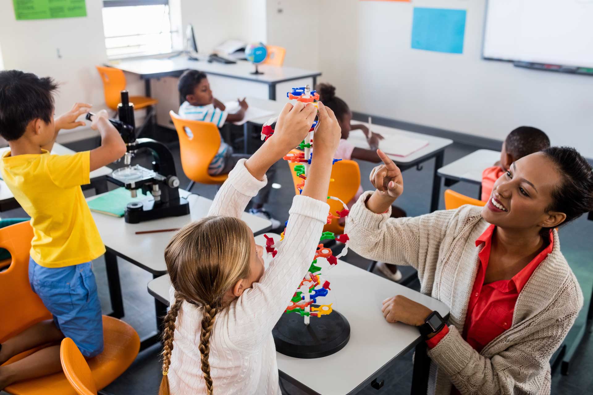 Teacher with group of young children in a classroom setting.