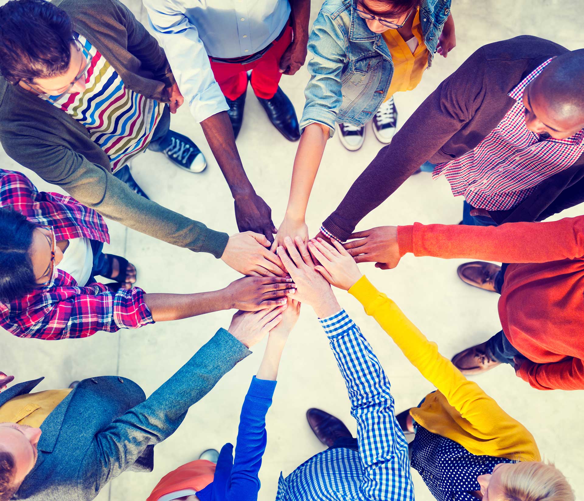 Group of people putting hands together in a circle for teamwork. 
