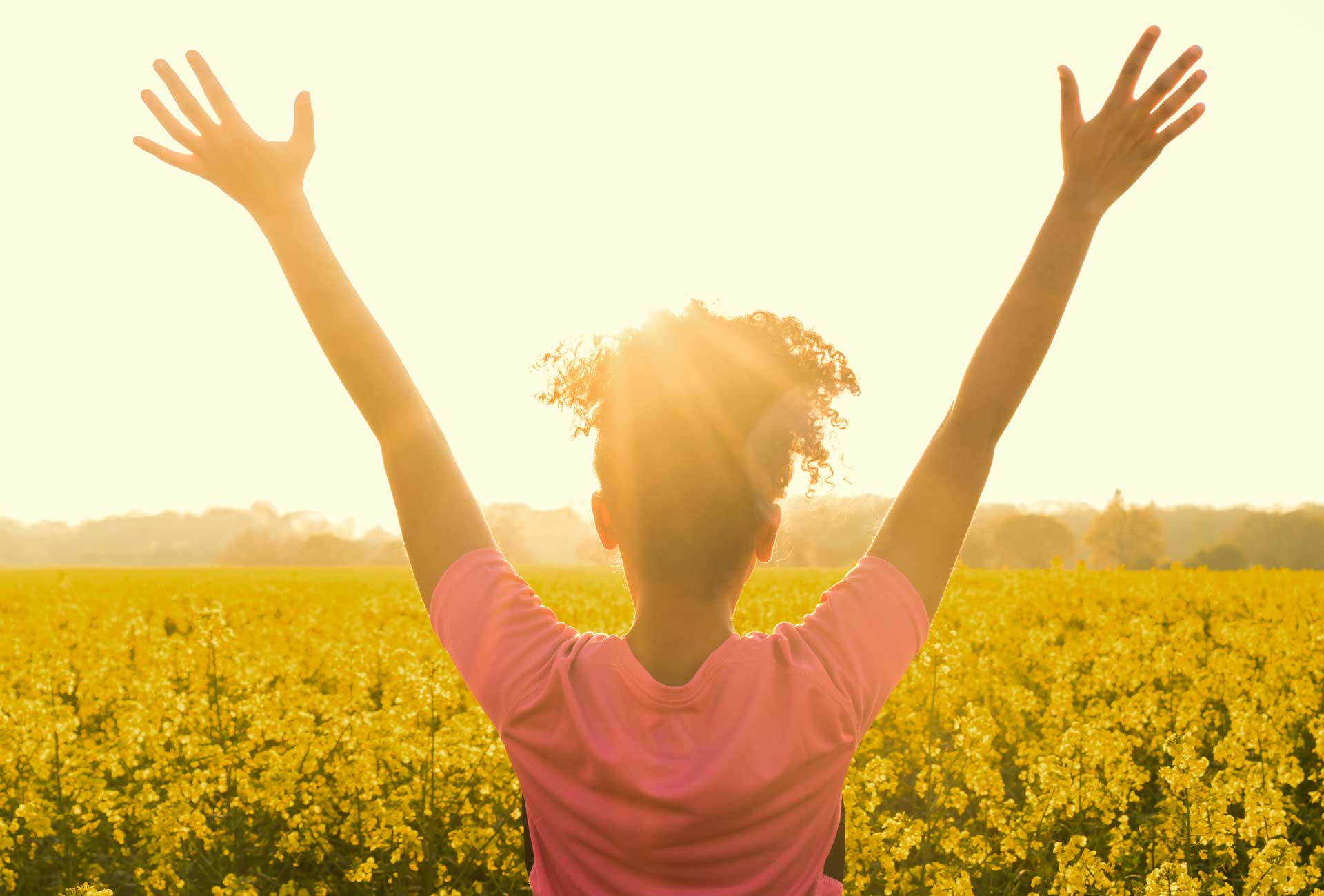 Girl standing in a flower field on a sunny day.