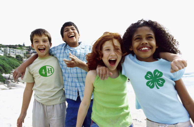 Four happy children hugging and smiling on a beach
