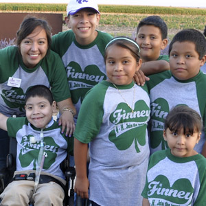 Six 4-H youth members and one adult all wearing green-sleeved white baseball shirts that read "Finney" on th e top and "4-H...join the club", bottom, both in white over a green clover