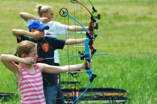 Three youth with compound bows aimed off-camera