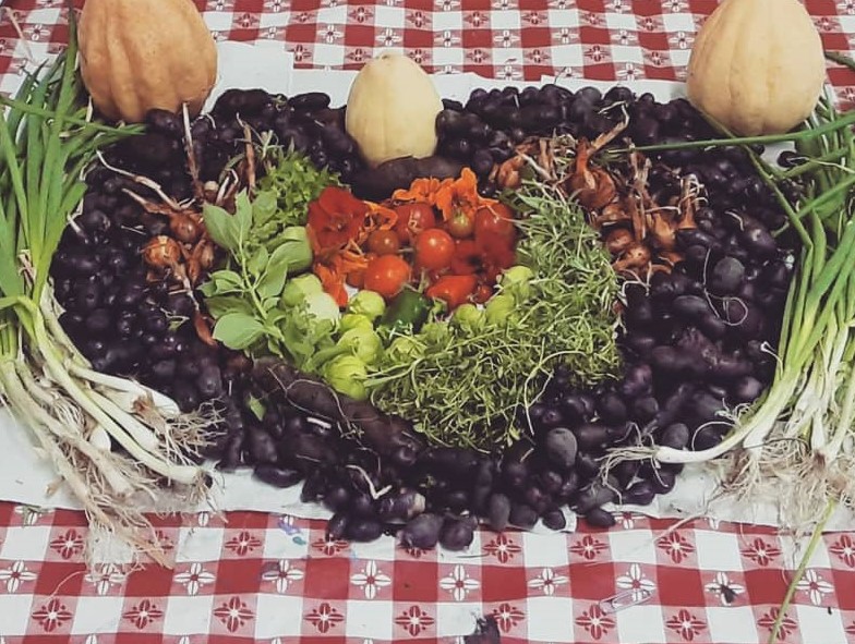 Potatoes, tomatoes, greens, herbs, and onions arranged in the shape of a colorful heart