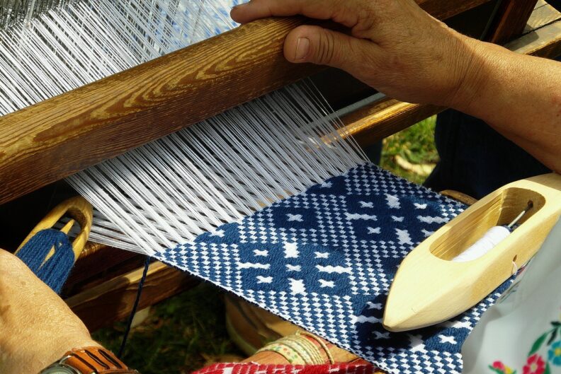 Close up image of hands working on a loom.