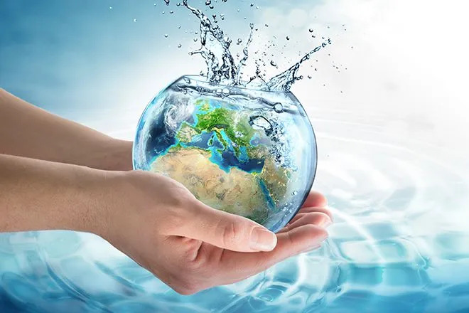 Hands holding a bowl of water that contains a reflection of the earth in the bowl.