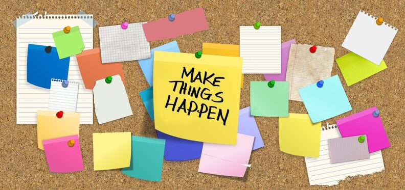 A bulletin board covered in a variety of sticky notes. The one on top at center is yellow and says "Make Things Happen" on it