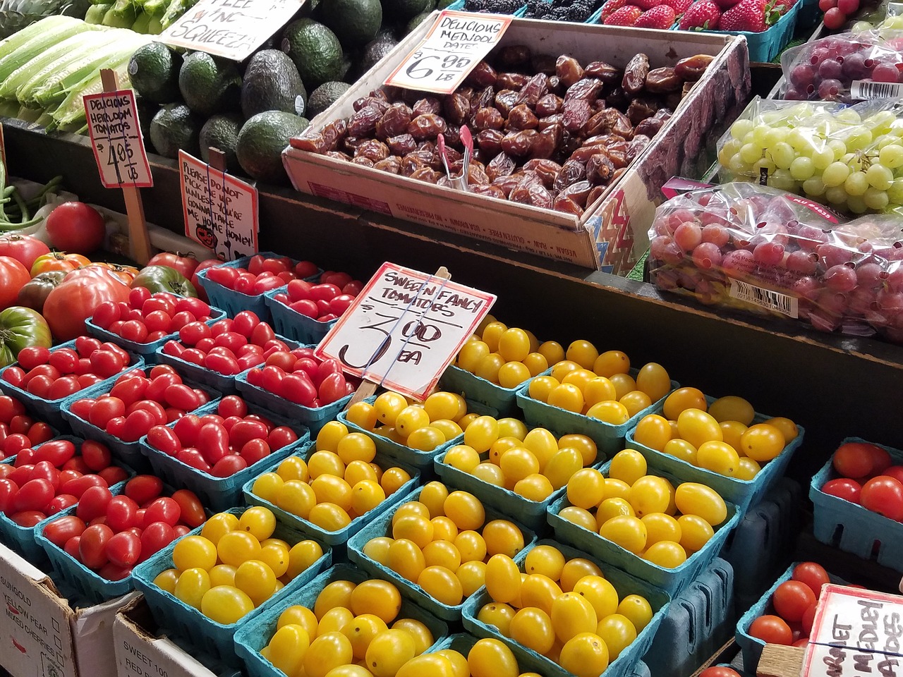 Varieties of tomatoes, avocados, grapes, and other produce at a farmers market stand