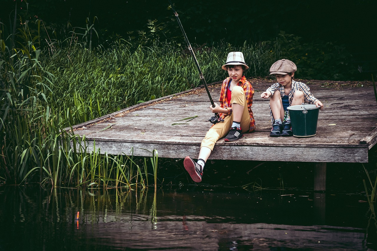Two children sit on a dock fishing