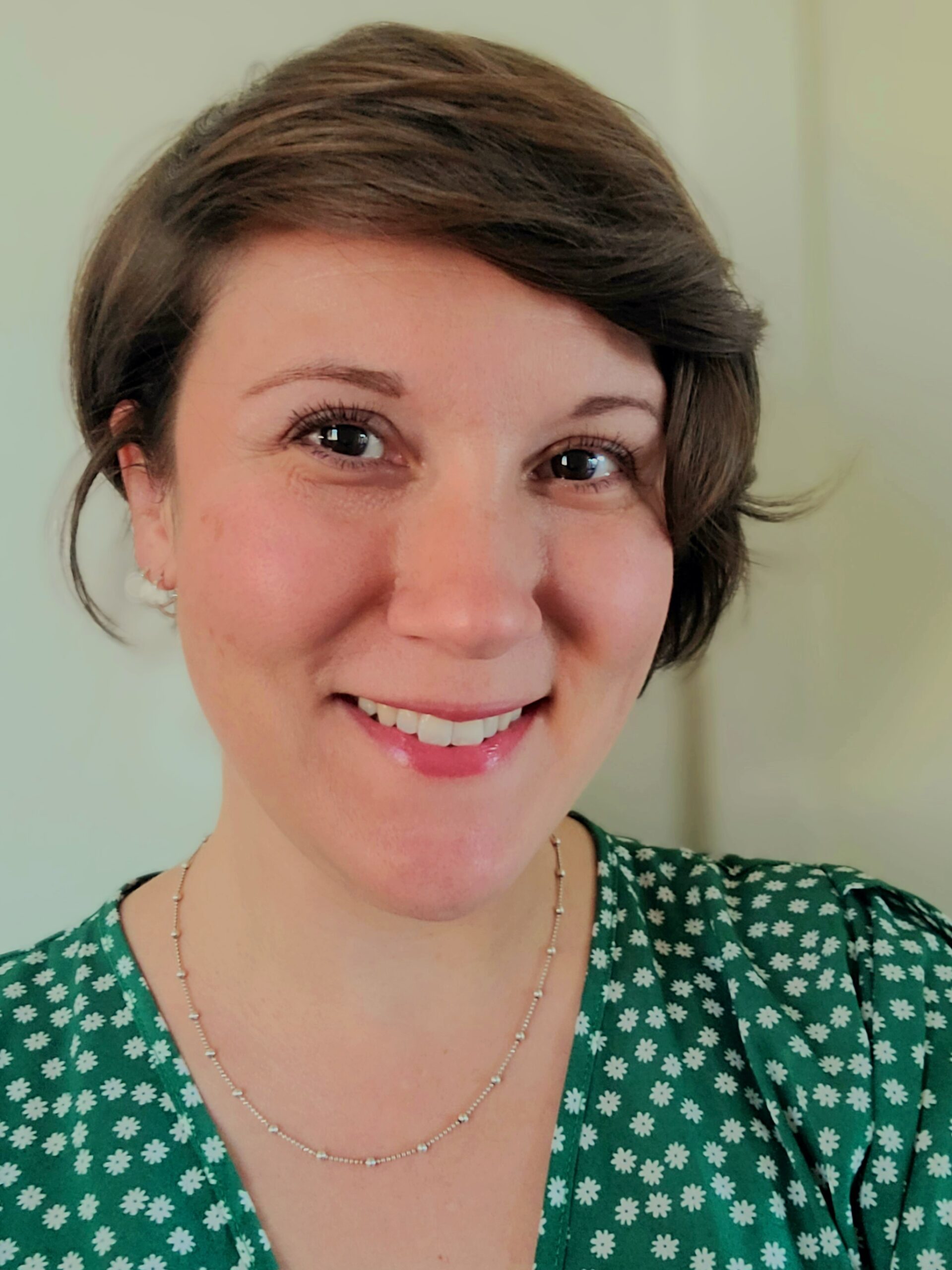 Smiling light skinned person with short brown hair in a green spotted shirt