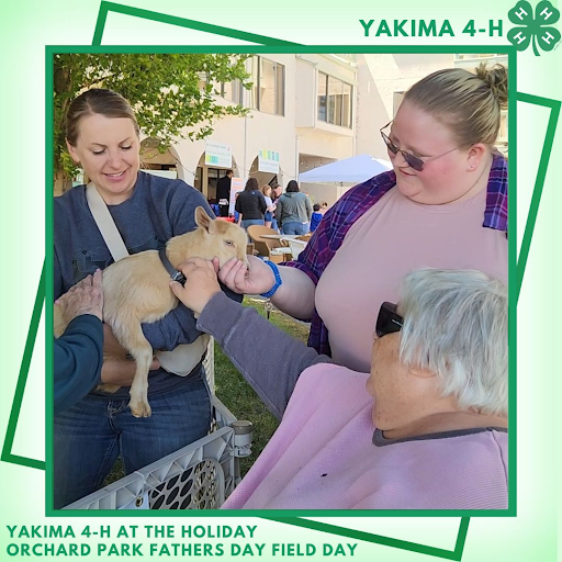 A 4-H youth holds a goat for an adult to pet