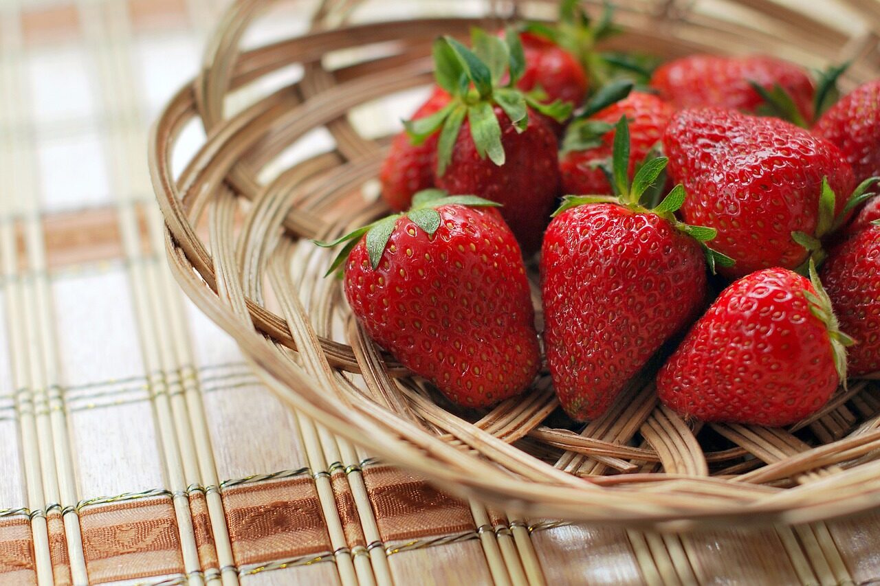 A group of strawberries in a woven basket-like tray on a brown plaid tabletop.