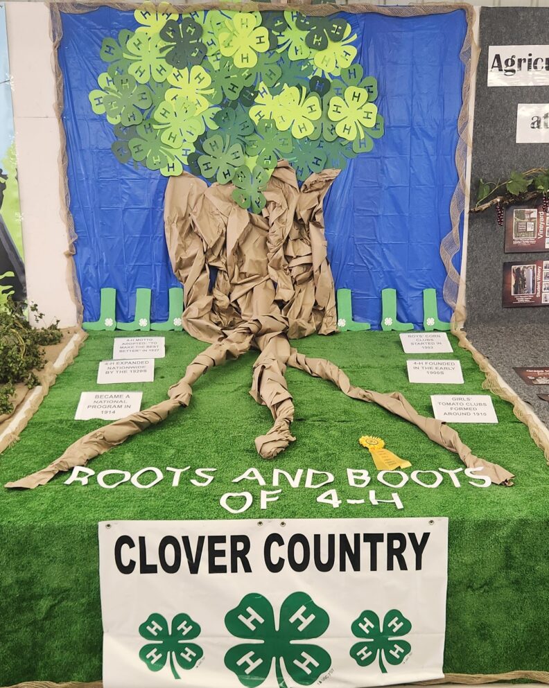 Clover Country 4-H Clubs fair display at Yakima Valley Fair and Rodeo that says "Roots and Boots of 4-H" with a tree made of paper with 4-H clovers as the leaves.