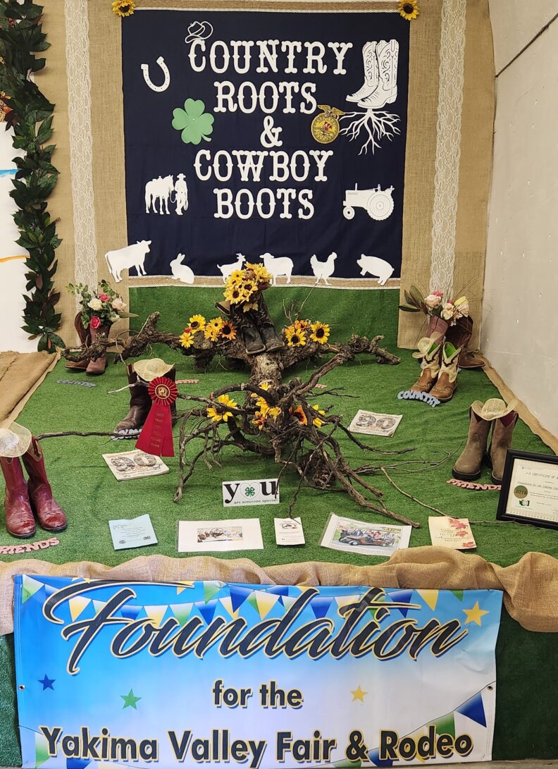 A 4-H Clubs fair display at Yakima Valley Fair and Rodeo that says "Country Roots and Cowboy Boots" surrounded with boots, sunflowers and 4-H paper memorablia. 