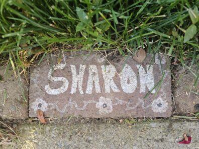 Brick in the garden edge, painted with the name: Sharon.