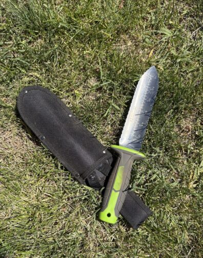 Tori Tori knife laying on the grass with its sheath.