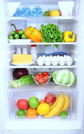 Produce, eggs, milk, and containers in an open refrigerator.