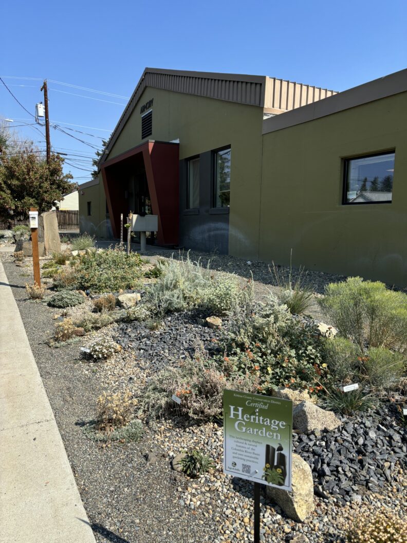Gardenscape outside of a commercial building featuring native plants and the sign "Heritage Garden" in the foreground.