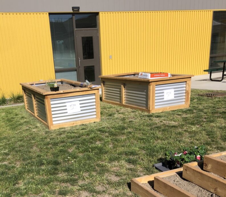 Two raised garden boxes labeled with grade levels at a local elementary school.