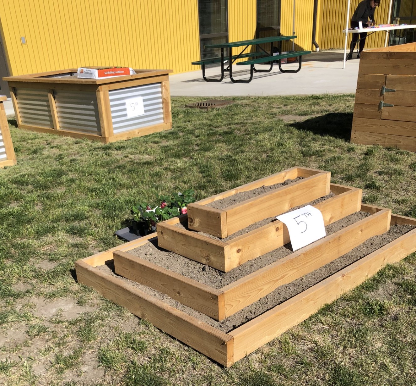 Two different style planter boxes labeled with grade levels at an elementary school.