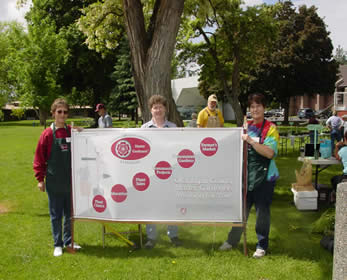Three people holding Master Gardener sign.